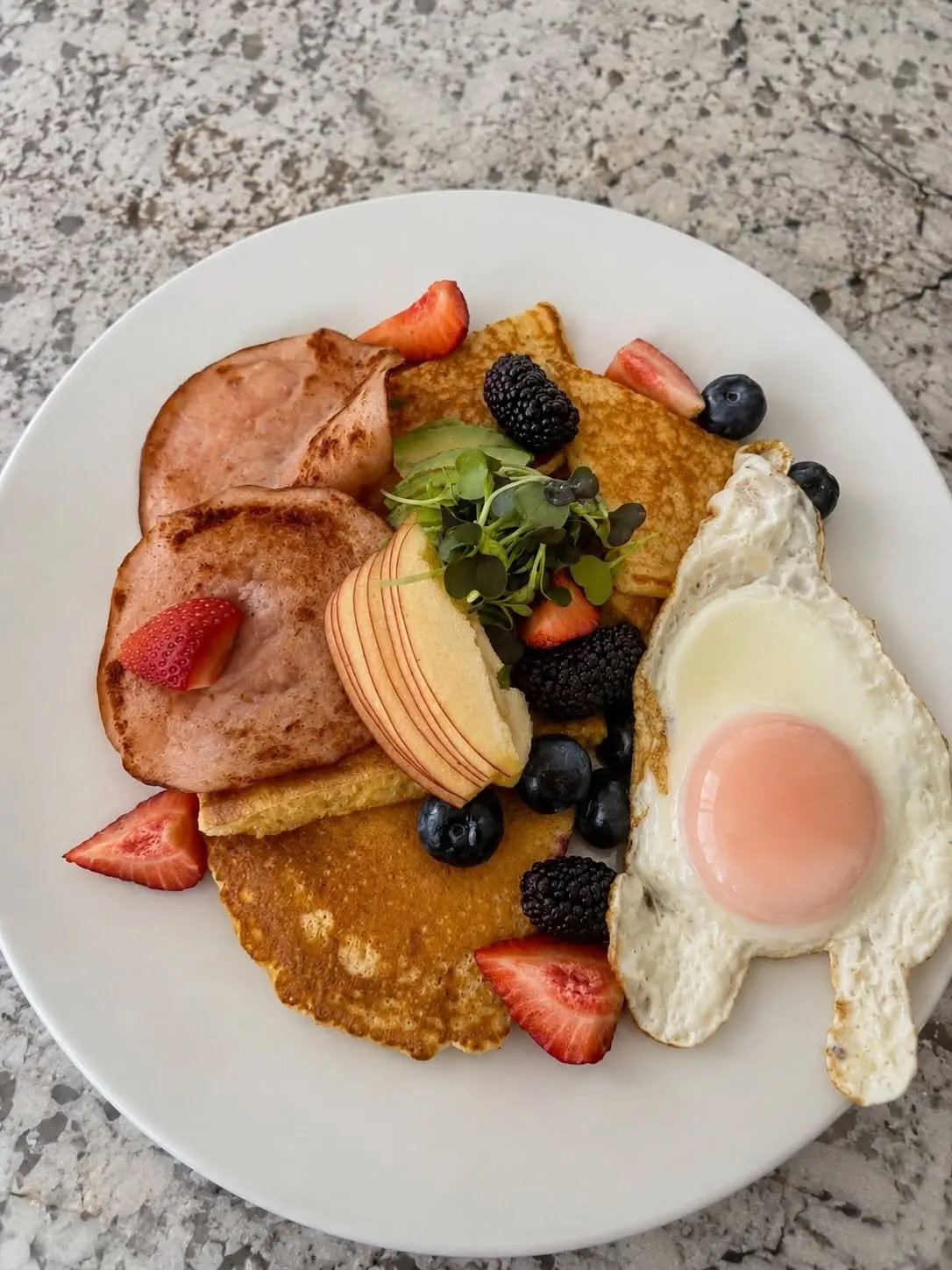 Brunch plate with pancakes, eggs, ham and fresh berries